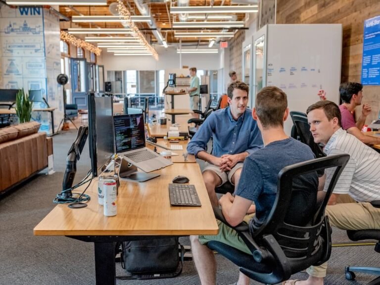 Group of professionals discussing the layout of a newsletter on a large monitor